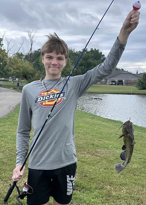 Kade showing the fish he caught on the Boys Ranch Town