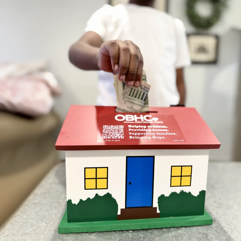 child placing money in obhc birthday bank